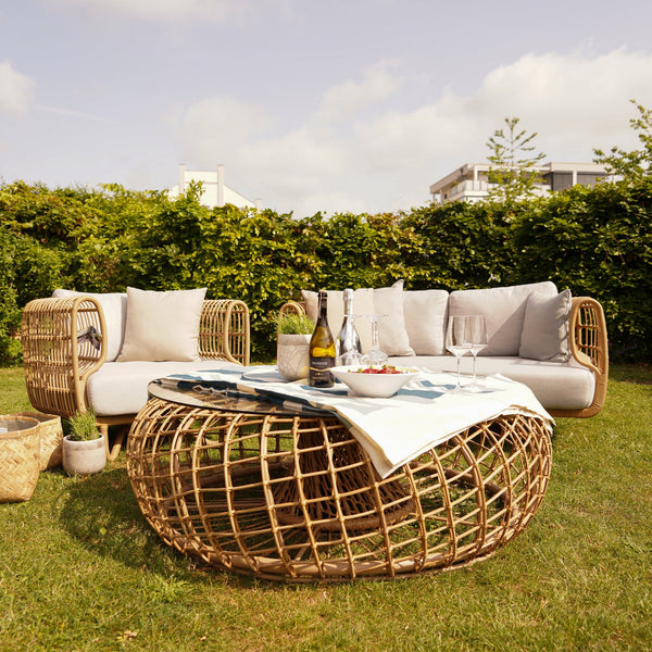 Cane-Line Garten Lounge aus der Nest Kollektion: Elegantes Sofa, Sessel und runder Tisch, wetterbeständig und pflegeleicht.